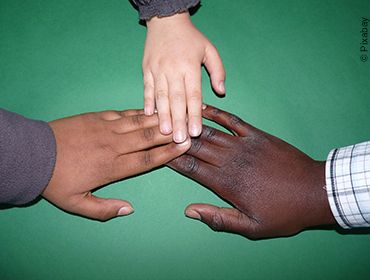 Drei Kinder unterschiedlicher Nationalitäten legen ihre Hände freundschaftlich aufeinander